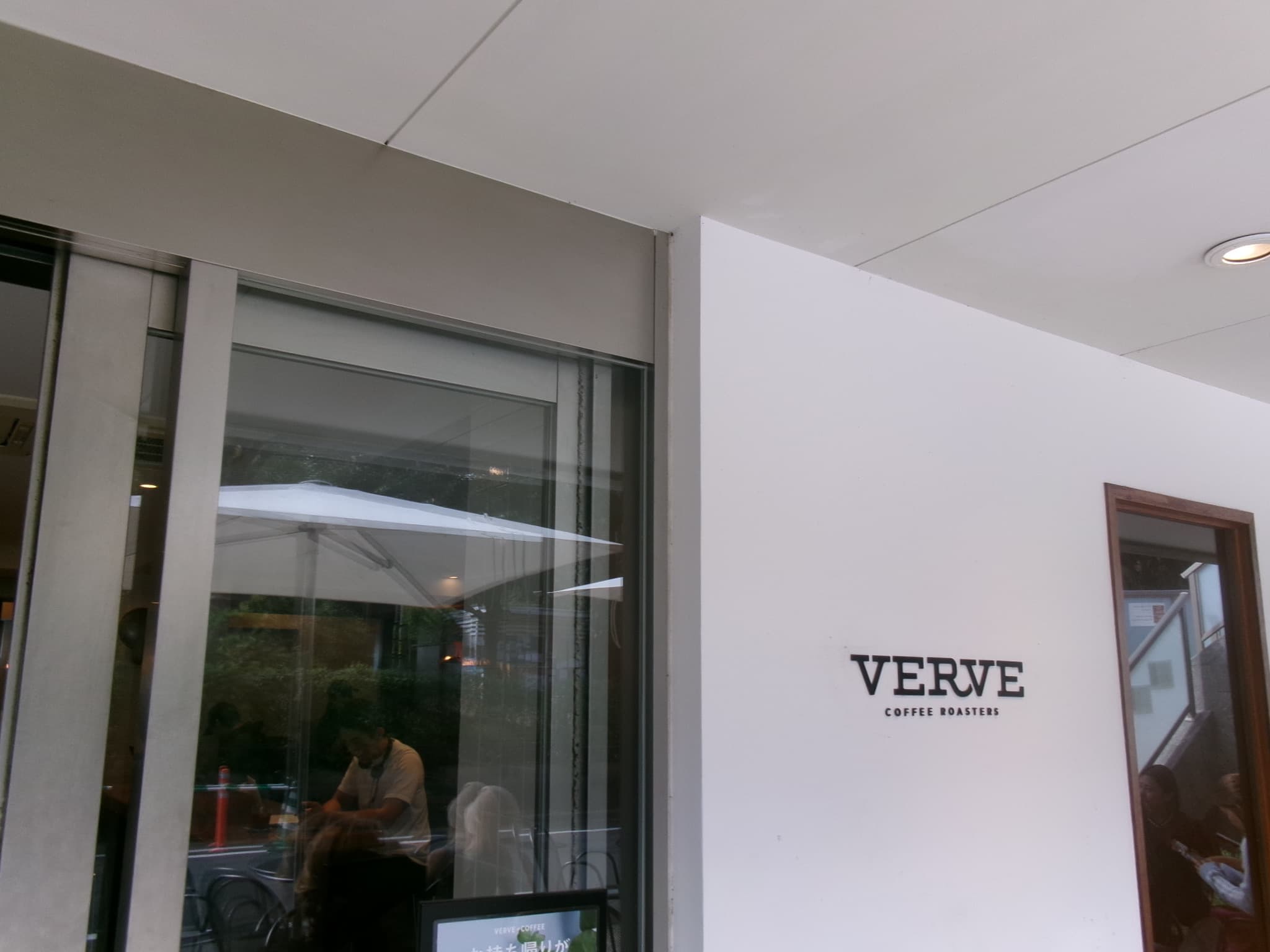 VERVE COFFEE ROASTERS 代代木公園店的外觀 - 白牆上的VERVE標誌與玻璃門